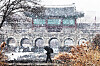 A pedestrian walks through falling snow in front of the Hwahongmun Gate of the Hwaseong Fortress in Suwon, Gyeonggi, on Jan. 12. The fortress, built in the 18th century, was designated as a World Heritage site by Unesco in 1997.