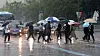 People holding umbrellas cross a main street in downtown Seoul on Thursday as the rainy season begins. [NEWS1]