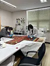 Experts carefully brush dust off the hwarot from Lacma [CULTURAL HERITAGE ADMINISTRATION]