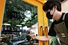 An employee at a coffee shop in Seoul writes a notice on Sunday explaining new social distancing rules to take effect the following day, which would limit business hours of restaurants and cafes in areas under Level 4 to 9 p.m. from the current 10 p.m. [NEWS1]