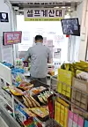 A customer at a convenience store in Songpa District, southern Seoul, uses an automated counter to buy products on Tuesday. Following the government's announcement on Tuesday that it would raise next year's minimum wage by 5.1 percent to 9,160 won ($8), a coalition of convenience store owners released a statement saying they ″cannot pay that amount″ even if they want to. ″We cannot accept a minimum wage raise that does not take into account the realities of convenience owners and other self-employed workers.″ [YONHAP]