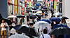 People holding umbrellas pass through a street in Myeong-dong, central Seoul, on Saturday. [YONHAP]
