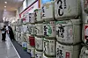 Visitors to the Seoul Sake Festival 2024 look at wooden containers of sake in southern Seoul on Sunday. The festival displays around 500 different types of premium sake. [YONHAP]
