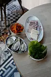 Bossam, or steamed pork, comes with many different sides to eat together, such as oyster, and radish seasoned with gochugaru. [AGENCE NEROLI]