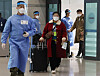 A Korean quarantine official escorts travelers from China for PCR testing at Incheon International Airport on Sunday.. [YONHAP]