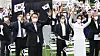 President Yoon Suk-yeol, left, and first lady Kim Keon-hee wave Korean flags during a ceremony marking the 77th Liberation Day on the front lawn of the presidential office in Yongsan District, central Seoul, on Monday. [JOINT PRESS CORPS]
