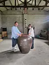 Lee Suk-yl, left, and Yoo Gi-ok, owners of Mokdo Brewery in Goesan, North Chungcheong, pose for a photo with one of the earthen jars used decades ago to make makgeolli, fermented rice wine. Many of the unused tools and equipment are displayed at the brewery so that visitors can learn about the transformation of Korea's makgeolli (traditional Korean rice wine)-making tradition. [YIM SEUNG-HYE]