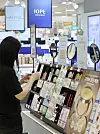A customer tries out beauty products at a cosmetics display aisle in a Seoul supermarket on Thursday. [YONHAP]