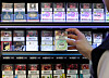 A convenience store employee organizes cigarette products on display in central Seoul. [NEWS1]