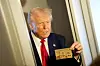 U.S. President Donald Trump holds ″The Trump Card″ as he speaks with journalists onboard Air Force One en route to Miami, Florida, U.S., April 3. [REUTERS/YONHAP]