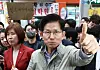 People Power Party candidate Kim Moon-soo holds his thumb up while eating fishcakes in Pohang, North Gyeongsang, on May 6. One supporter in the background holds up a sign saying ″Don't yield.″ [NEWS1]