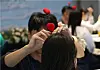 A participant puts a hair accessory on a partner's head during a mass blind date program arranged by the Haeundae District office in Busan last May. [YONHAP]