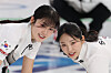 Korean women's curling team members Seol Ye-eun, left, and Kim Su-ji sweep during the delivery of the final stone in the fourth end of their round-robin match against Japan at the Cortina Curling Olympic Stadium during the 2026 Milan-Cortina Winter Olympics in Cortina d’Ampezzo, Italy, on Feb. 15. [YONHAP]