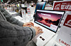 A store worker examines a laptop displayed at an electronics store in Seoul on Jan. 25. [YONHAP]