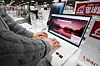 A store worker examines a laptop displayed at an electronics store in Seoul on Jan. 25. [YONHAP]