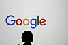 A woman walks by a giant screen with a Google logo at an event at the Paris Google Lab on the sidelines of the AI Action Summit in Paris on Feb. 9. [AP]