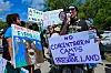 Demonstrators hold signs as they protest U.S. President President Donald Trump's visit to a migrant detention center, dubbed ″Alligator Alcatraz,″ located at the site of the Dade-Collier Training and Transition Airport in Ochopee, Florida, on July 1, 2025. [AFP/YONHAP]
