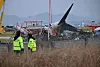 Police officers stand guard as firefighters and recovery teams work at the scene where a Jeju Air Boeing 737-800 series aircraft crashed and burst into flames at Muan International Airport in Muan, South Jeolla on Dec. 30, 2024. [AFP/YONHAP]