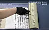 A staff at the National Palace Museum in central Seoul, carefully spreads out one of the scrolls during the press conference held on Wednesday. [KOREA HERITAGE SERVICE]