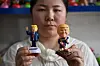 Salesperson Cassie poses with product samples depicting US President Donald Trump at a factory specialising in solar powered plastic gadgets in Yiwu, China's eastern Zhejiang province on April 11, 2025. Like countless other companies in the manufacturing powerhouse of Zhejiang province, its products are geared largely towards export -- a sector freshly menaced by Donald Trump's roiling of the global economy and increasingly brutal China tariffs. [AFP/YONHAP]