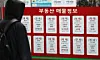 A pedestrian looks at house listings at a real estate agency in Gangnam District, southern Seoul, on Feb. 8. [NEWS1]