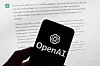 The OpenAI logo is displayed on a mobile phone in front of a computer screen with output from ChatGPT in Boston on March 21, 2023. [AP/YONHAP]