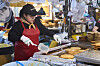 A stall owner at Gwangjang Market in central Seoul, makes mung bean pancakes while wearing a black hat and a t-shirt from K-fashion label Matin Kim. [HAGO HOUSE]