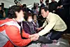 Democratic Party leader Lee Jae-myung, right, holds hands with people displaced by ongoing wildfires at a gymnasium in Uiseong, North Gyeongsang, on March 27. [JOINT PRESS CORPS]