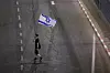 A demonstrator walks on a road with an Israeli flag during a protest to demand the immediate release of hostages held in Gaza since the October 7, 2023, attack on Israel by Hamas in Tel Aviv on June 28. [REUTERS/YONHAP]