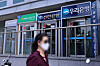 A pedestrian passes by ATMs from banks including KB Kookmin Bank and Woori Bank in Seoul on June 3. [YONHAP]