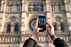 A woman takes a picture with her smartphone as people queue to visit the Notre-Dame Cathedral soon after its restoration in Paris on Dec. 27, 2024. [REUTERS/YONHAP]