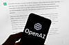 The OpenAI logo is displayed on a mobile phone in front of a computer screen with output from ChatGPT on March 21, 2023, in Boston. [AP/YONHAP]