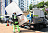 A sanitation worker in Dobong District, northern Seoul, wears a wearable robot while loading a mattress into a vehicle during a demonstration event for the device held at the district office plaza on May 14. [DOBONG DISTRICT OFFICE]