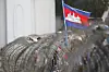 A Cambodian National flag flutters above barbed wire set up by police near the Council of Ministers building while garment workers gather for a rally in Phnom Penh, Cambodia on Dec. 30, 2013. [AP/YONHAP]
