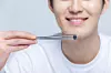 A man poses while holding a bean with metal chopsticks [GETTY IMAGE BANK]