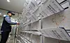 A postal worker places a booklet-style pamphlet for the presidential election into a mailbox at an apartment in Gangnam District, southern Seoul on May 19. [YONHAP]