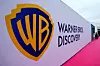 Warner Bros. Discovery logo on a white wall beside a pink carpet in Cannes.