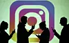 Silhouettes of mobile users are seen next to a screen projection of Instagram logo in this picture illustration taken March 28, 2018. [REUTERS/YONHAP]