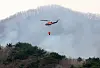 A helicopter equipped for firefighting flies over a wildfire in Hadong, South Gyeongsang on March 28. [NEWS1]