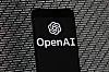 The OpenAI logo appears on a mobile phone in front of a computer screen with random binary data, on March 9, 2023, in Boston. [AP/YONHAP]