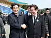 People Power Party floor leader Kweon Seong-dong, left, and Democratic Party leader Lee Jae-myung, right, shake hands after attending a ceremony at the Daejeon National Cemetery on March 28. [JOINT PRESS CORPS]