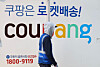 A Coupang worker walks in front of a delivery truck with the company logo printed on it in a logistics center in Seoul on Dec. 17. [YONHAP]