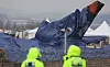 A waterproof tarp covers the tail section of the destroyed Jeju Air plane to protect it from the rain at Muan International Airport in South Jeolla on Sunday. [YONHAP]