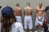 U.S. Secretary of Homeland Security Kristi Noem, left, looks at prisoner during a tour at the Terrorist Confinement Center in Tecoluca, El Salvador, on March 26. [AP/AFP/YONHAP]