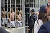 Homeland Security Secretary Kristi Noem, right, looks a prisoner in a cell during a tour of the Terrorist Confinement Center in Tecoluca, El Salvador, on March 26. [AP/YONHAP]