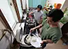 Sokkoko Han, left, a foreign worker employed by a subcontractor at a major shipyard in Geoje, South Gyeongsang, and his colleague boil a chunk of pig’s trotter and cook rice for dinner in their two-room apartment on June 5. [JOONGANG ILBO]