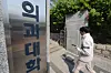 A student walks into the campus of a medical school in Seoul on April 16. [YONHAP]