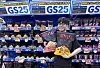 A model holds a bag of GS25’s Netflix Jumbo Popcorn in front of a dedicated display selling GS25 private label products at Don Quijote discount stores in Japan from mid-May. [GS RETAIL]