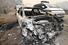 A police officer checks a burned-out passenger car on the road leading to Maejeong-ri Village in Yeongdeok County, North Gyeongsang, on March 26. Police said that three nursing home residents who were evacuated in a passenger car as the wildfire spread died in the fire. [NEWS1]