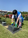 A volunteer cleans a gravestone of a fallen British soldier who died while defending South Korea during the 1950-53 Korean War at UN Memorial Cemetery in Korea in Busan in an undated photo. [UN MEMORIAL CEMETERY IN KOREA]